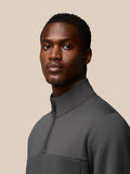 Male model in charcoal Castore Flex Lifestyle 1/4 Zip top seen from a three-quarter rear angle