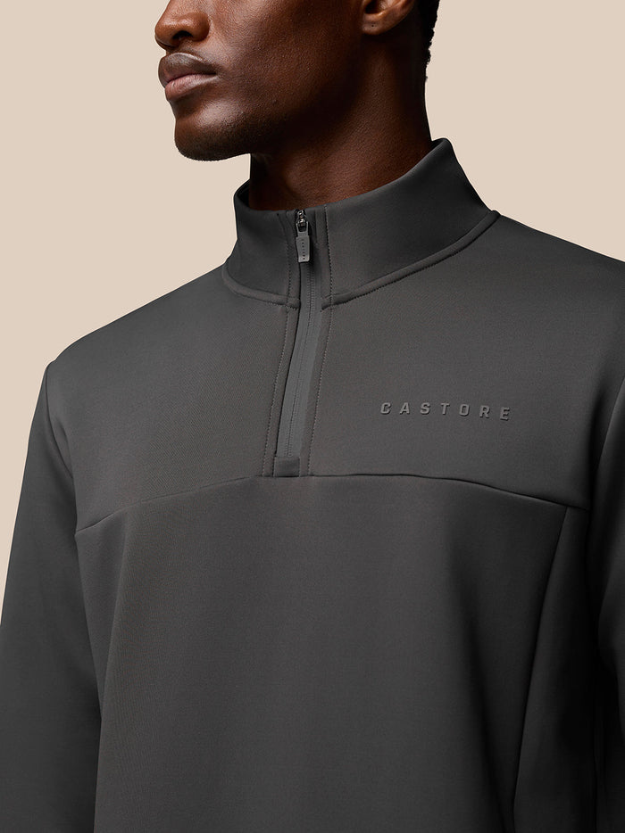 Close up of a man wearing a charcoal Castore Flex Quarter Zip top with a high collar and front zipper