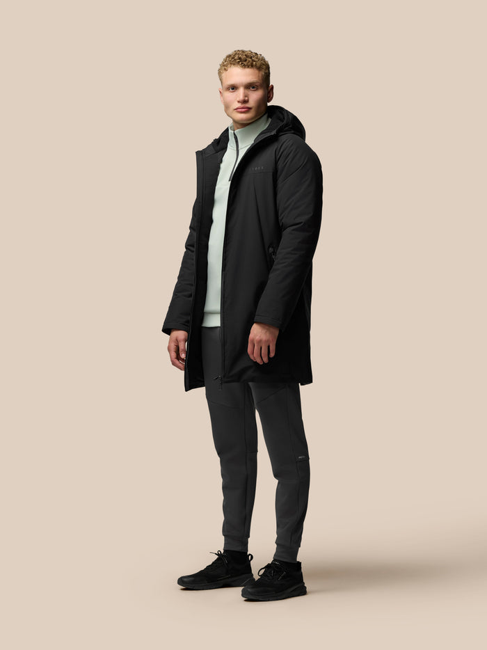 Model wearing longline black water resistant jacket with hood, front zip and external pockets