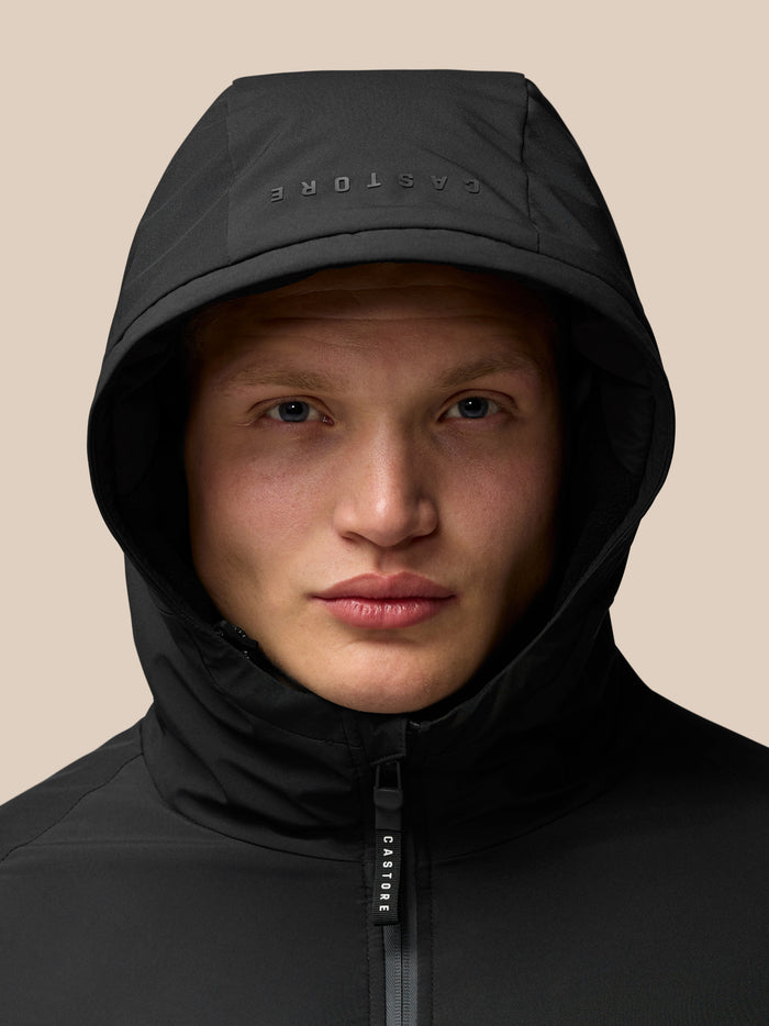 Close up of a model wearing a black longline hooded jacket featuring ProTek water-resistant fabric.