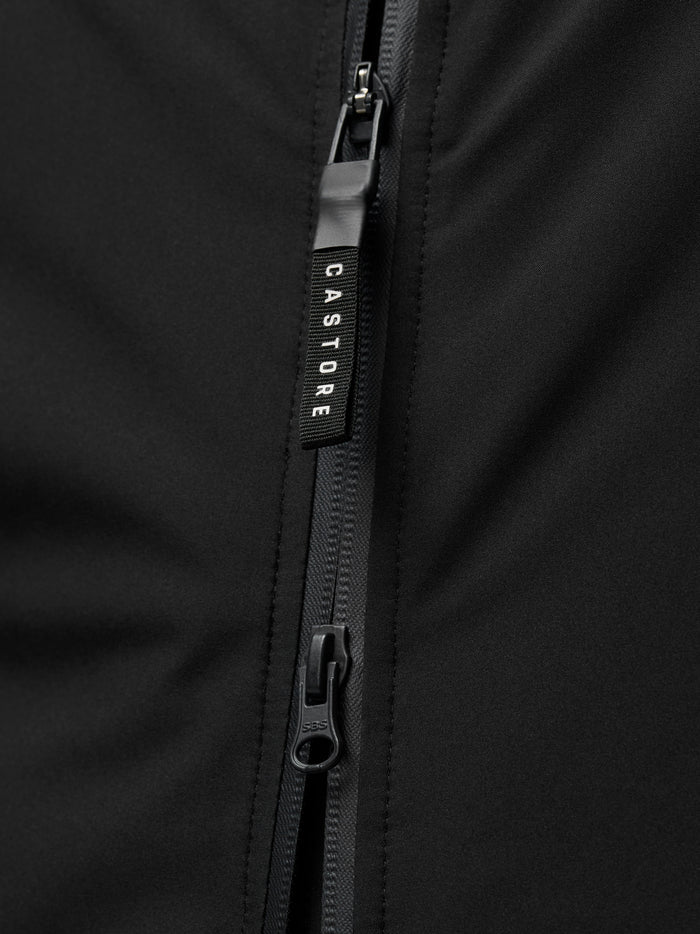 Zipper close-up on the black jacket with Castore pull and ProTek branding visible at the cuff area