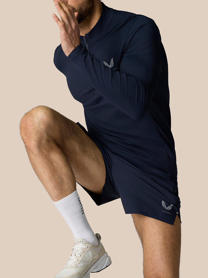 Male model wearing Zone Training 1/4 Zip Top in midnight navy kneeling to show the long sleeves and high neck with zip