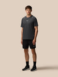 Male model wearing a dark Castore athletic T shirt with chest logo against a beige background