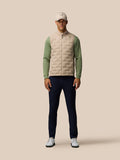 Front view of a man in Mushroom Golf Pinnacle lightweight hybrid gilet with quilted front panel and green sleeves