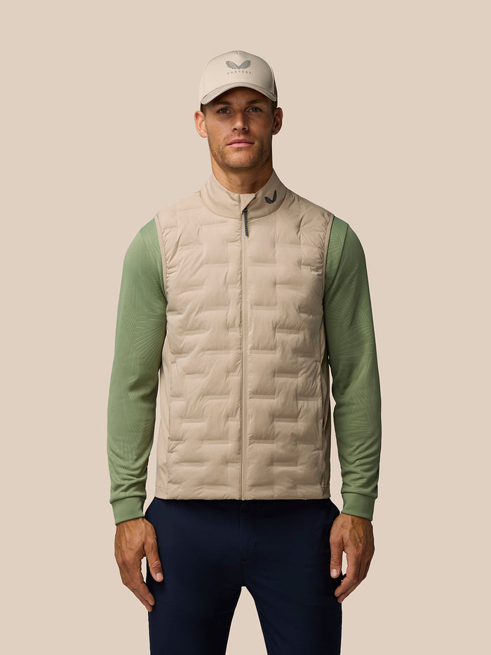 Man wearing Mushroom Golf Pinnacle Gilet with cap, showcasing quilted front panel and collar logo