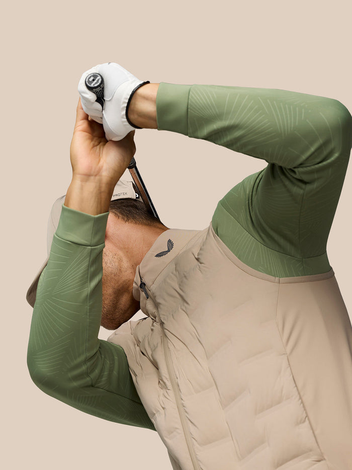 Model wearing Mushroom Golf Pinnacle Gilet with quilted front over green sleeves during a golf photo shoot