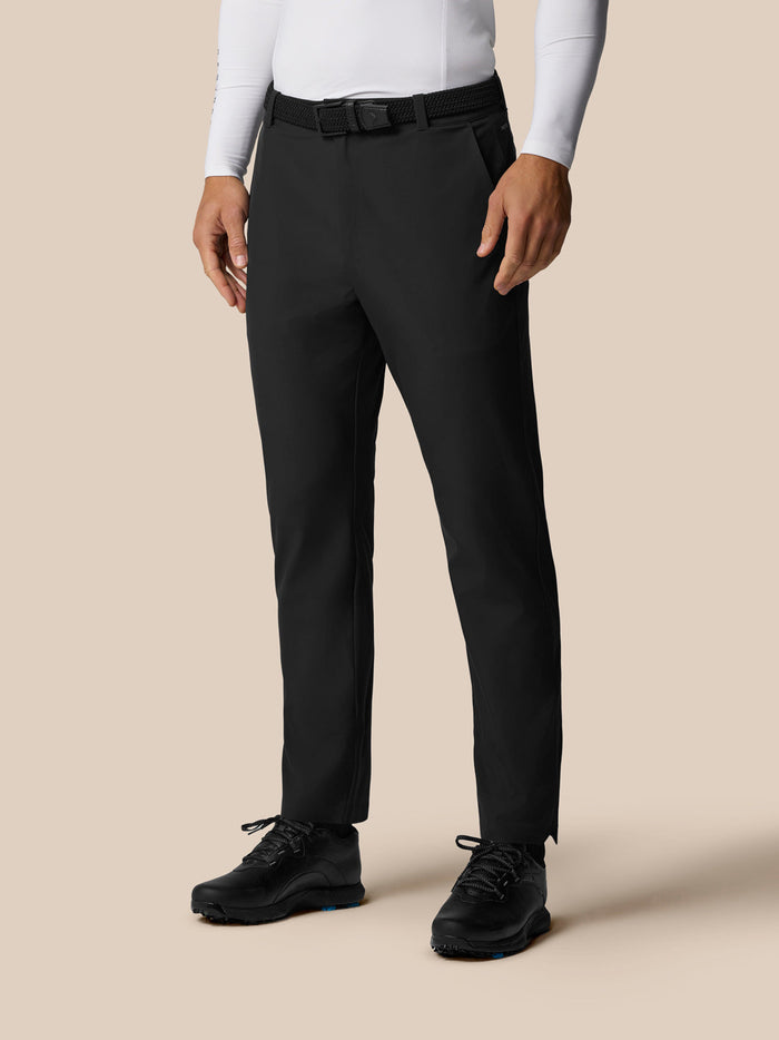 Front view of a male model wearing black Golf Pinnacle Winter Trousers with a black belt and golf shoes.