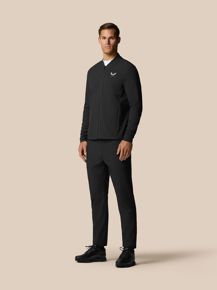 Back view of a male model wearing black Golf Pinnacle Winter Trousers with a slim belt and matching outerwear.
