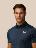 Close up of model wearing Golf Pinnacle Glow Polo in Midnight Navy showing all over stripes and left chest logo.
