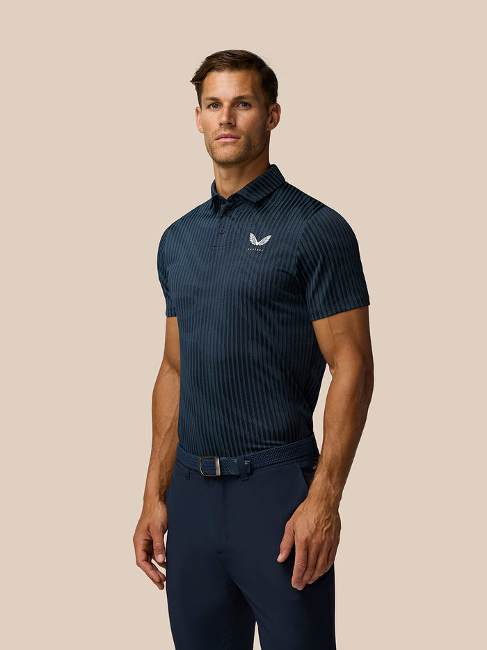 Male model wearing Golf Pinnacle Glow Polo in Midnight Navy with striped knit and left chest Castore logo.