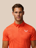 Close-up of male model in Golf Pinnacle Glow Polo Bright Orange with striped knit and left chest logo.