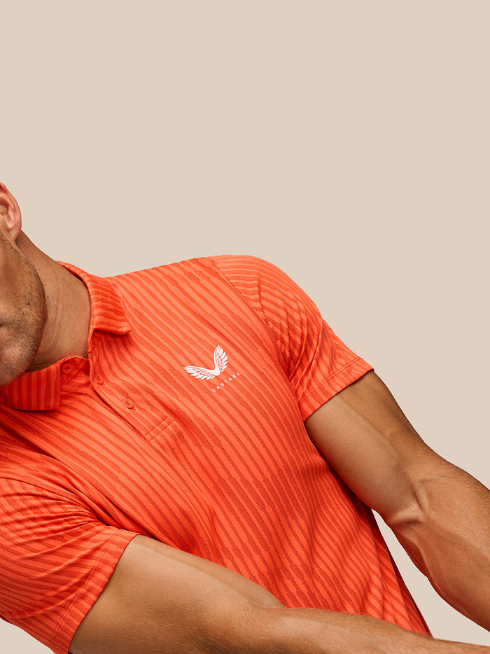 Close-up detail of Golf Pinnacle Glow Polo Bright Orange showing striped knit pattern and left chest logo.