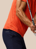 Side profile of a man in a bright orange striped golf polo, highlighting the knit stripe pattern and short sleeves
