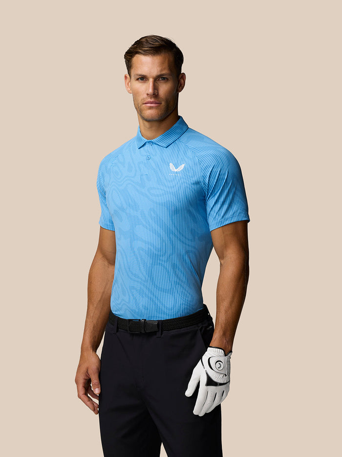 Male model wearing light blue glow printed golf polo with three button placket and Castore logo left chest