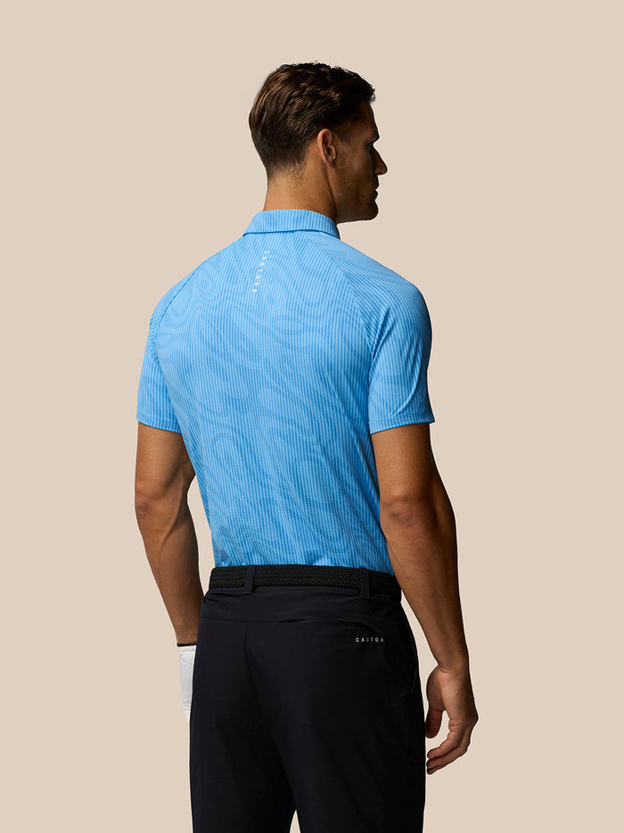 Back view of male model in a light blue glow printed polo displaying subtle fabric pattern