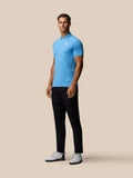 Model wearing light blue glow printed polo with three button collar and white Castore logo on chest