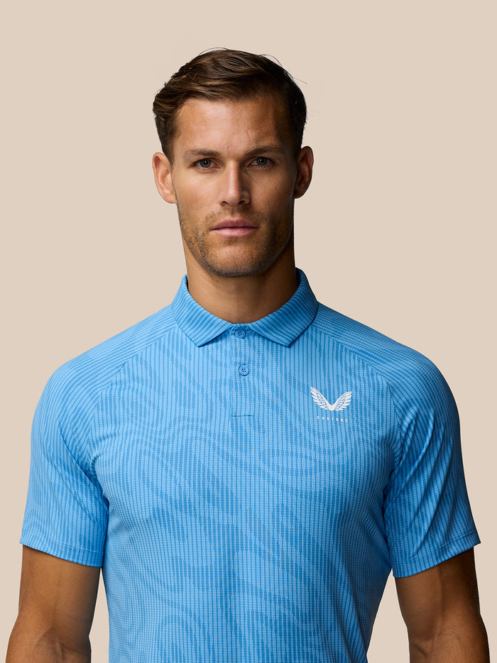 Male model wearing light blue Golf Club Glow Printed Polo with a white Castore logo on the chest