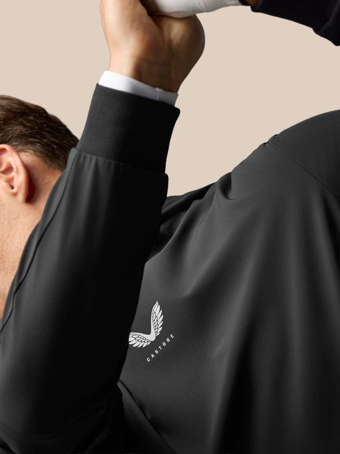 Close-up of a male model wearing the black Golf Pinnacle Performance Hoodie, highlighting the central Castore logo on the chest.
