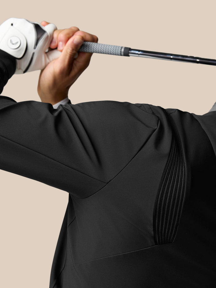 Golfer wearing a black Golf Pinnacle Performance Hoodie grips a golf club overhead.