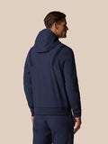 Back view of a man in a navy hooded jacket with emphasized hood and ribbed shoulder panels