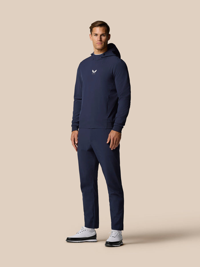 Full length shot of a man in a navy tracksuit with hooded top and matching pants wearing white sneakers