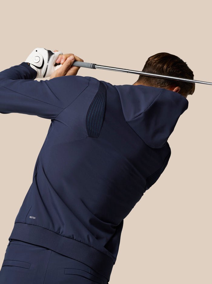Golfer wearing Midnight Navy Golf Pinnacle Performance Hoodie mid swing with a club