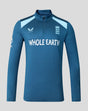 Front view of blue training midlayer top with zip collar and light blue shoulder panels displaying Whole Earth sponsor and Three Lions crest