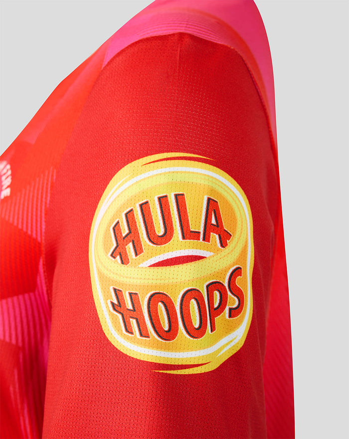 Close-up of red Welsh Fire women's jersey sleeve featuring the yellow Hula Hoops sponsor patch