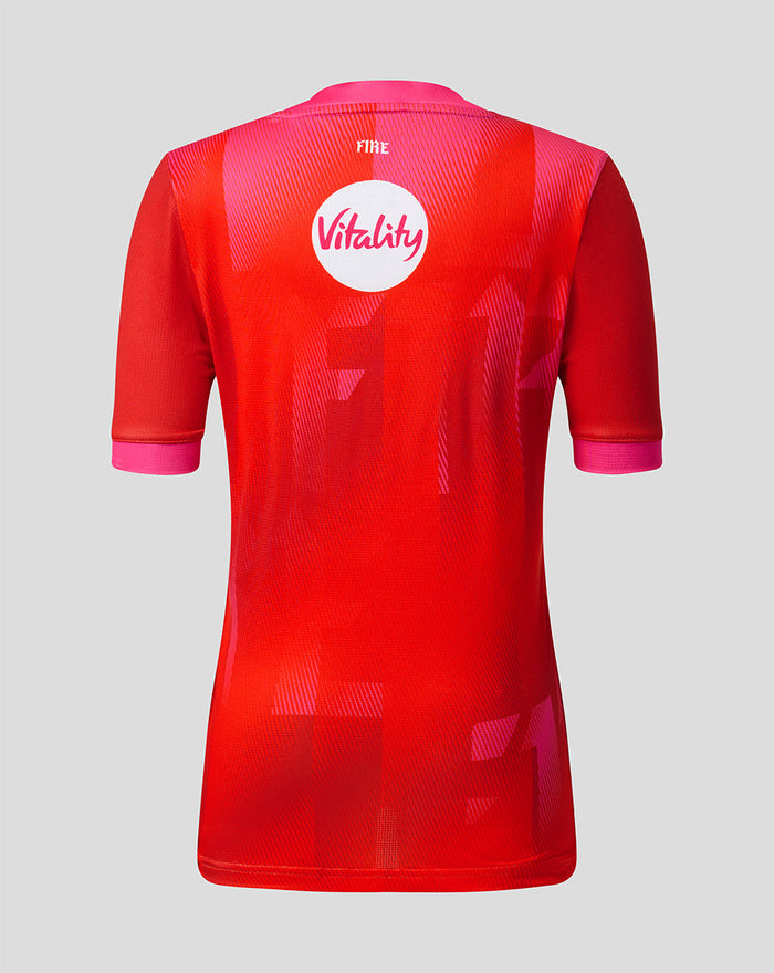 Back view of Welsh Fire 2026 junior short sleeve stretch jersey showing vibrant red geometric pattern and Vitality sponsor badge