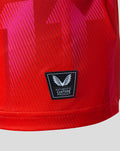Close-up of red Welsh Fire Junior 2026 jersey with authentic Castore badge and pink geometric print
