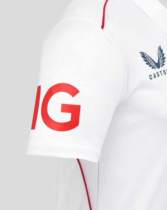 Close-up of sleeve showing bold red graphic on white shirt with red shoulder piping.
