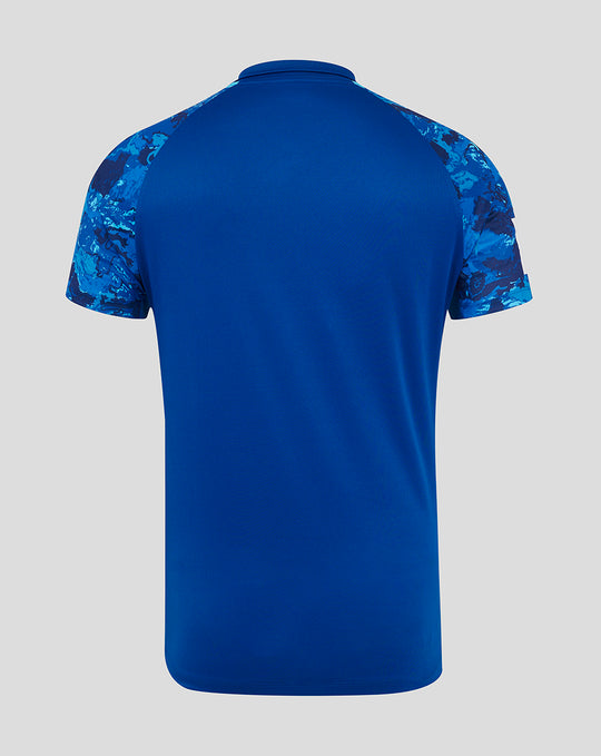 Back view of blue ODI cricket shirt with solid body and camo patterned raglan sleeves.