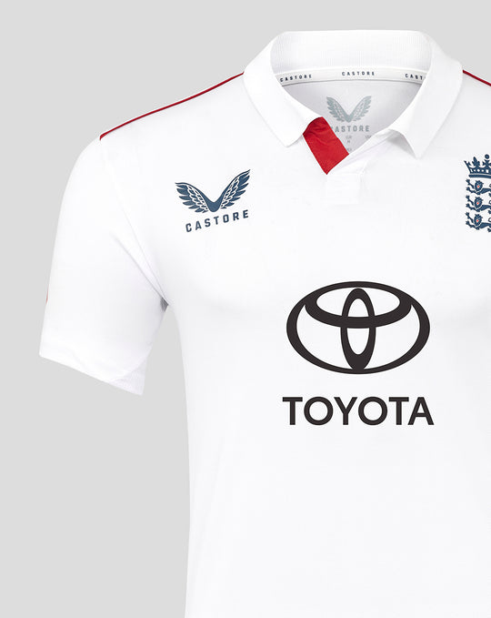 Close up of a white polo cricket shirt showing Castore branding on the left chest and a red sleeve stripe.