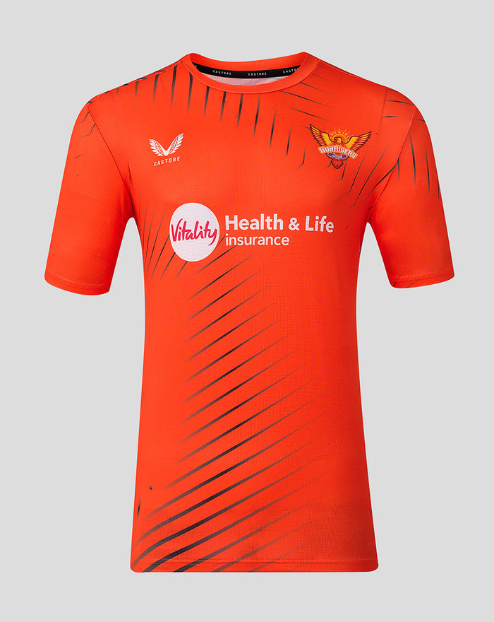 Front view of bright orange Sunrisers Leeds The Hundred training short sleeve shirt with diagonal dark stripes and sponsor logos