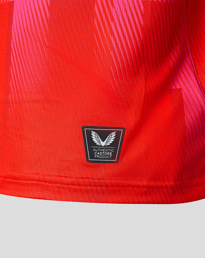 Close-up of red jersey fabric near the hem with the authentic Castore product badge.