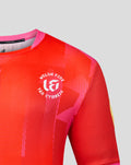 Shoulder and chest view of red Welsh Fire jersey featuring crest and bold geometric print