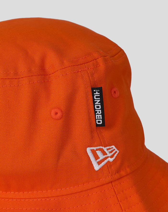 Close up of orange Sunrisers Leeds bucket hat showing New Era tag and embroidered white logo